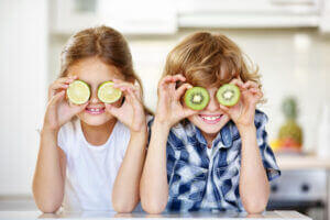 Young girls holding sliced veggies up to their eyes like glasses