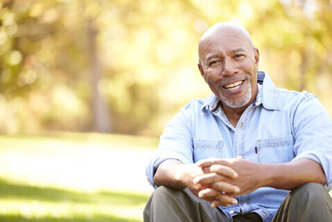 African American man sitting outside smiling at camera