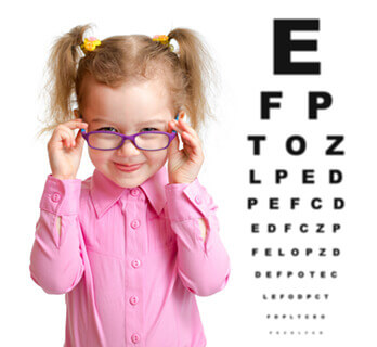 Little girl with glasses next to eye chart