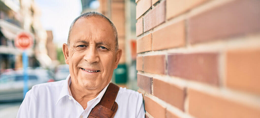 Mature man leaning against a brick wall