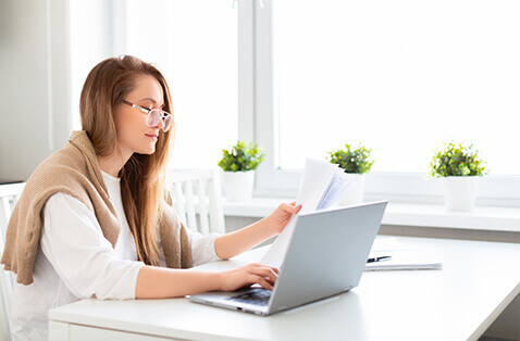 Woman on laptop with paperwork