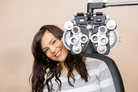 Woman smiling from behind phoropter